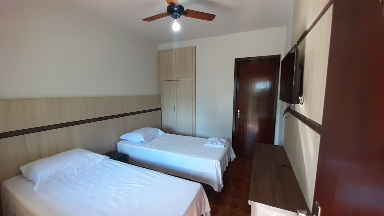 Quarto duplo com duas camas de solteiro e televisão